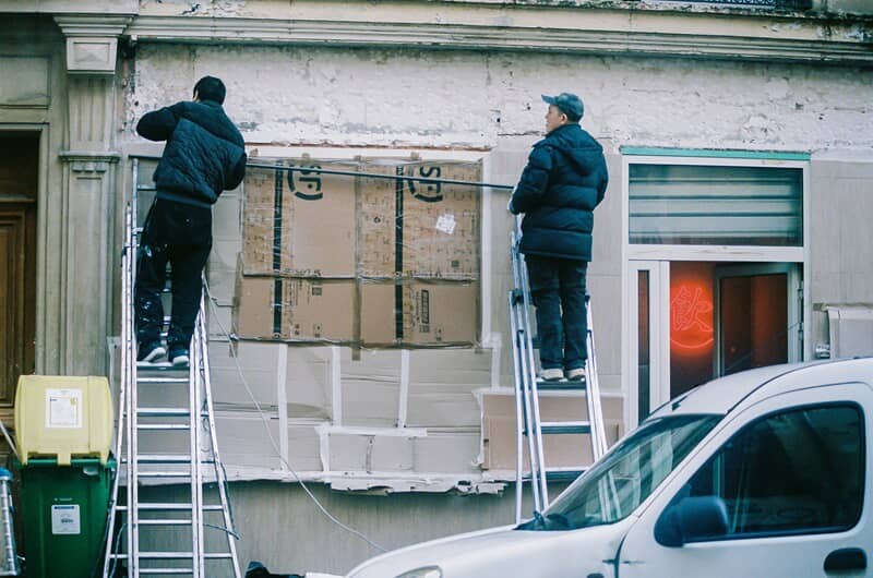An image of two men installing an exterior sign for a storefront.